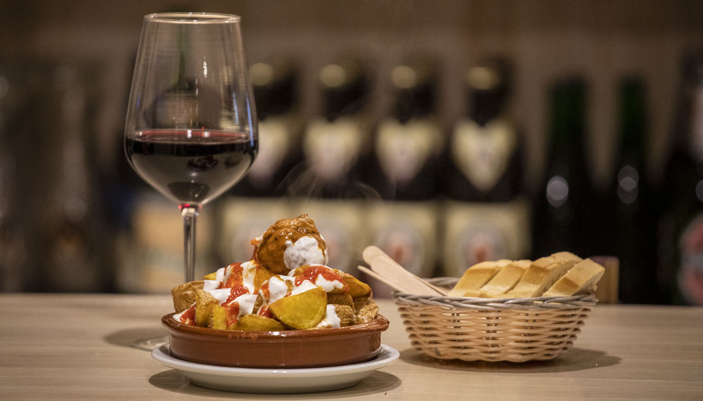 EL EMBAUCADOR. Albóndiga de la yaya Vero sobre cama de patatas bravas crujientes y copa de vino tinto singular Caudum (DOCa Rioja).