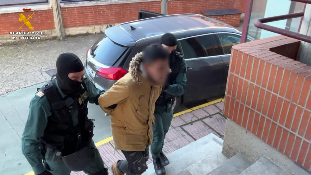 Dos guardias civiles conducen a uno de los arrestados. 