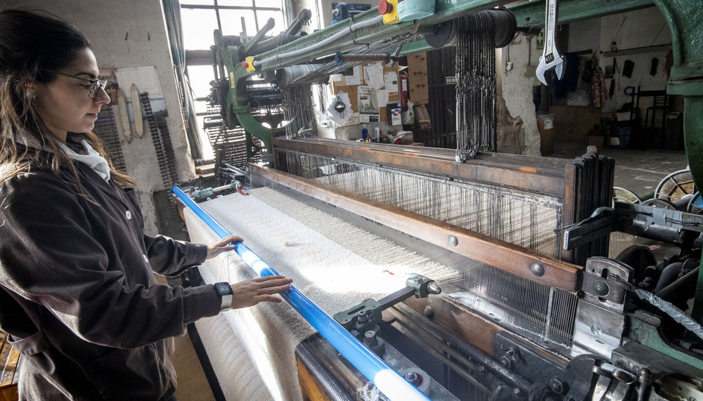 Una trabajadora teje con la ayuda de uno de los telares históricos de la fábrica artesana.