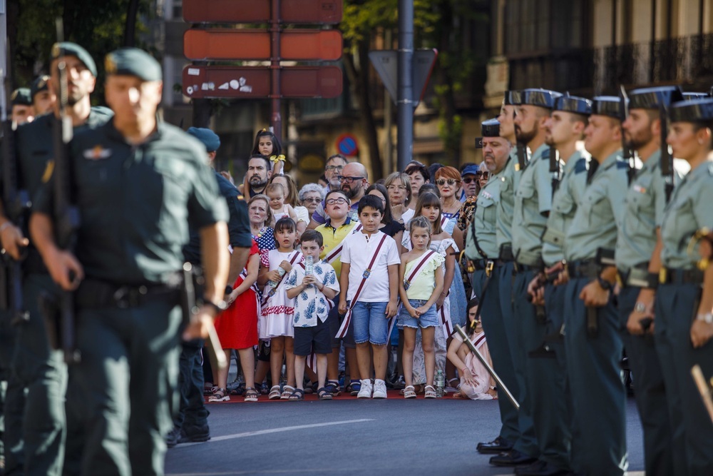 Un grupo de niños observa el desfile de una unidad de guardias civiles.