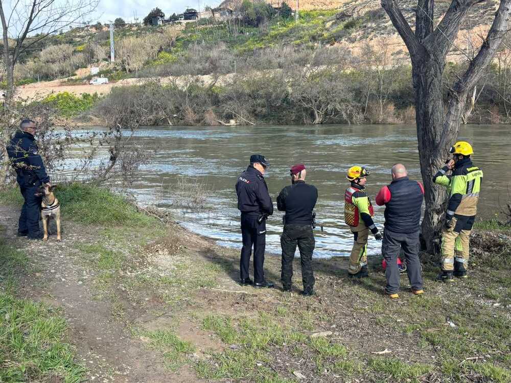 Policías y bomberos, con uno de los perros adiestrados, junto a la ribera del Ebro.